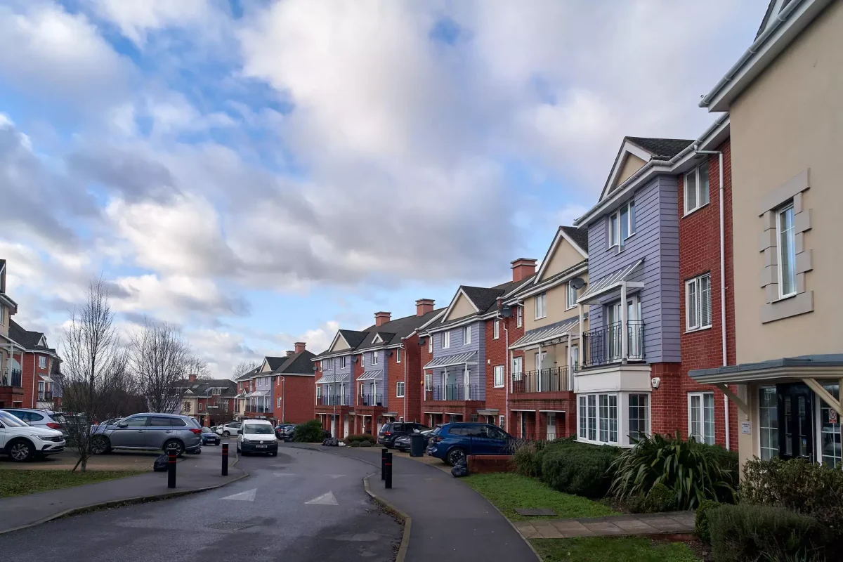 Row of colourful modern townhouses in Ruislip with parked cars along a residential street.