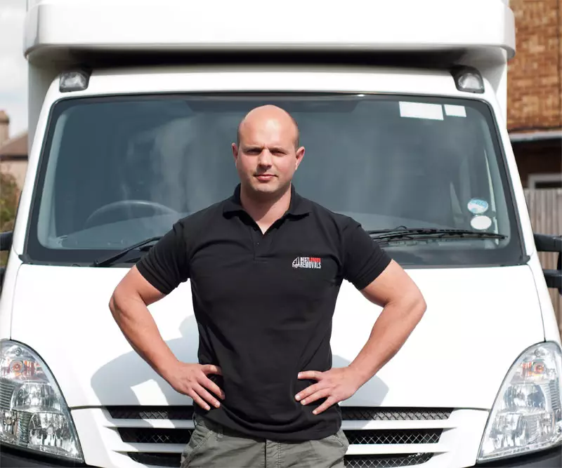 Man in branded uniform Best London Removals standing confidently in front of a white moving van