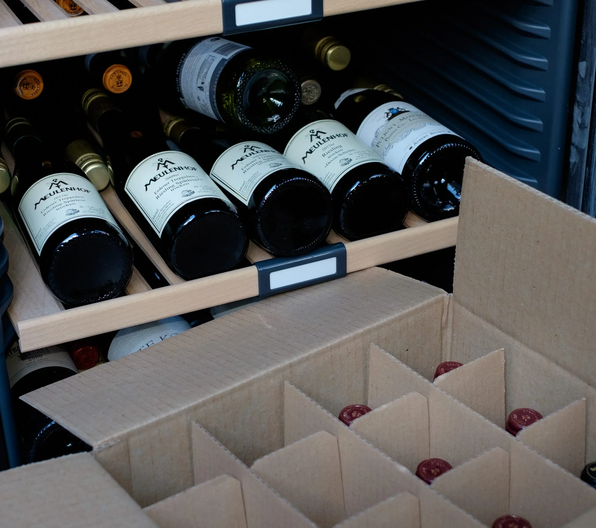 Wine bottles being packed into a cardboard divider box for safe transport during a house move.