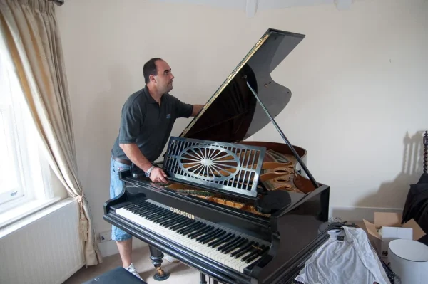 Mover preparing a baby grand piano for relocation
