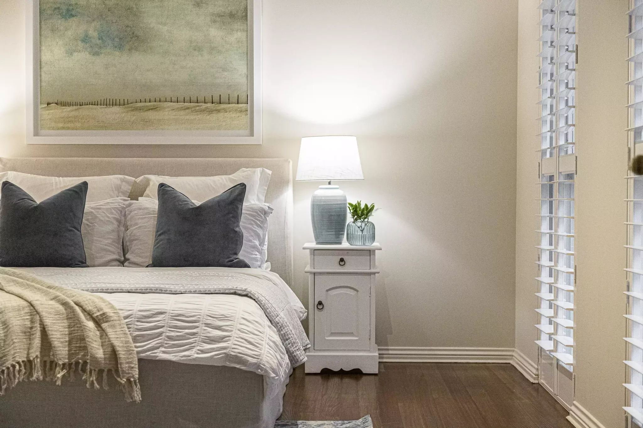Elegant bedroom with soft lighting, white furniture, and cosy bedding prepared for moving or staging.