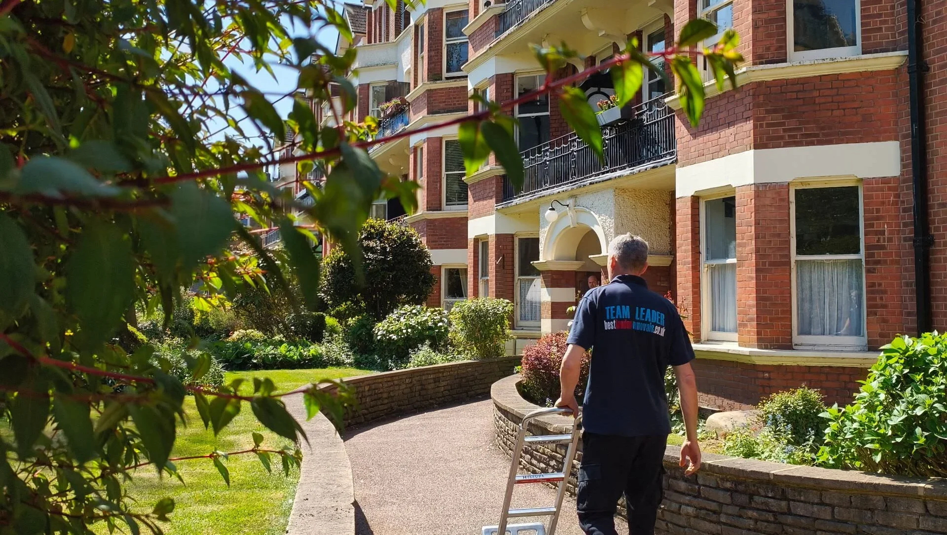 Team leader wheeling trolley towards red brick apartment building
