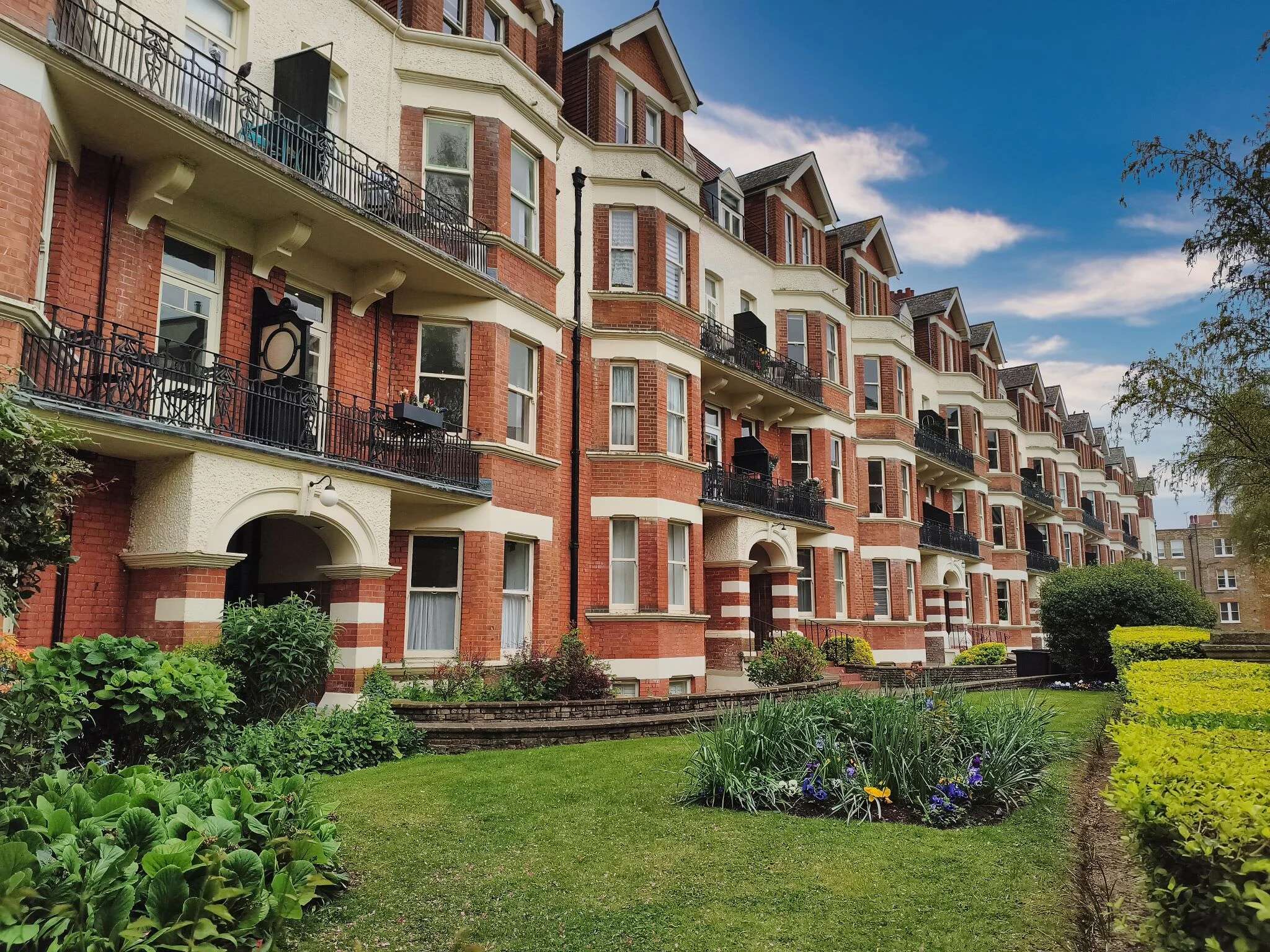 Grand Victorian red brick apartment buildings with manicured gardens