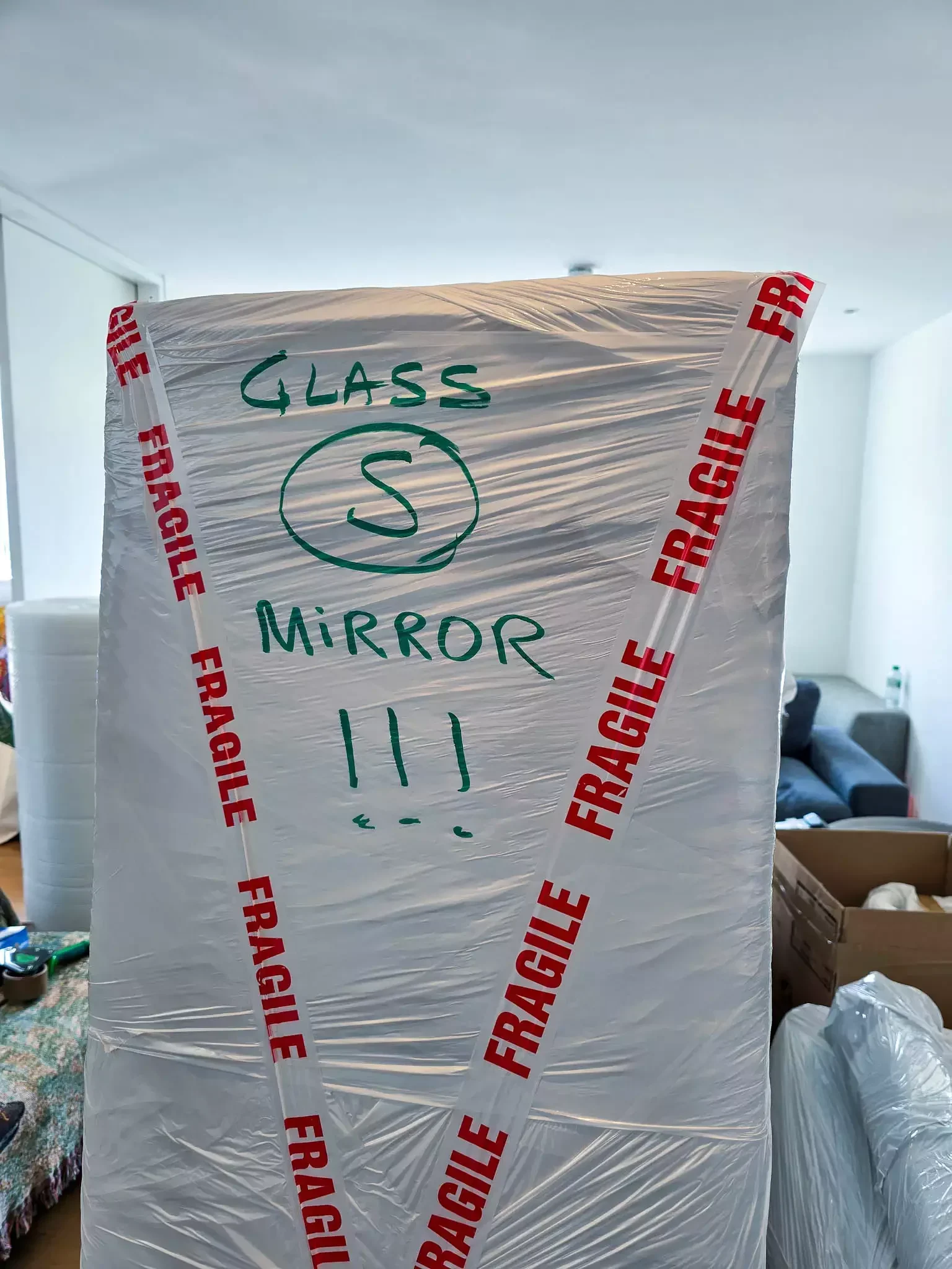 Wrapped and labelled fragile mirror prepared for transport during a house move.