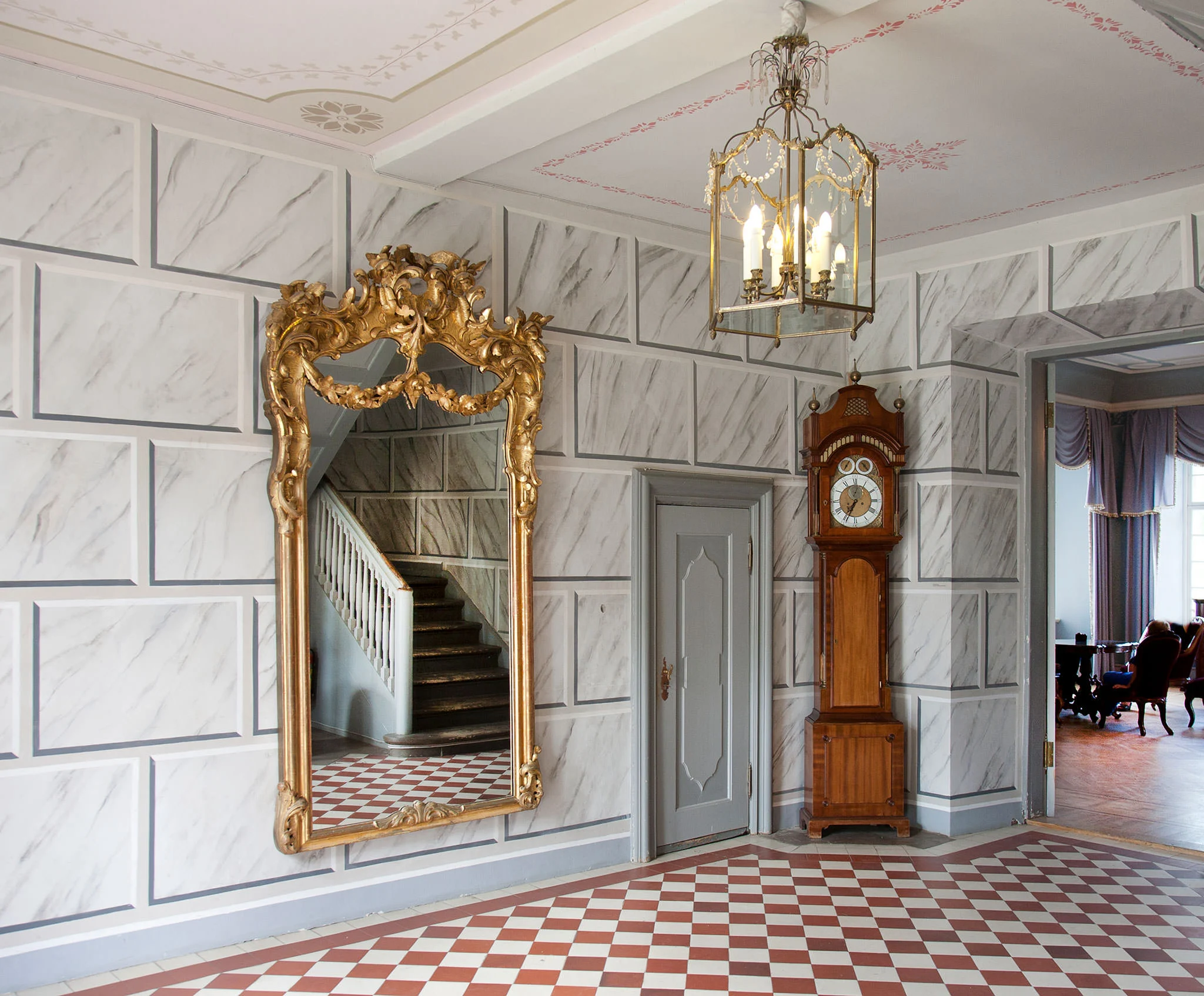 Ornate hallway with gold mirror and grandfather clock
