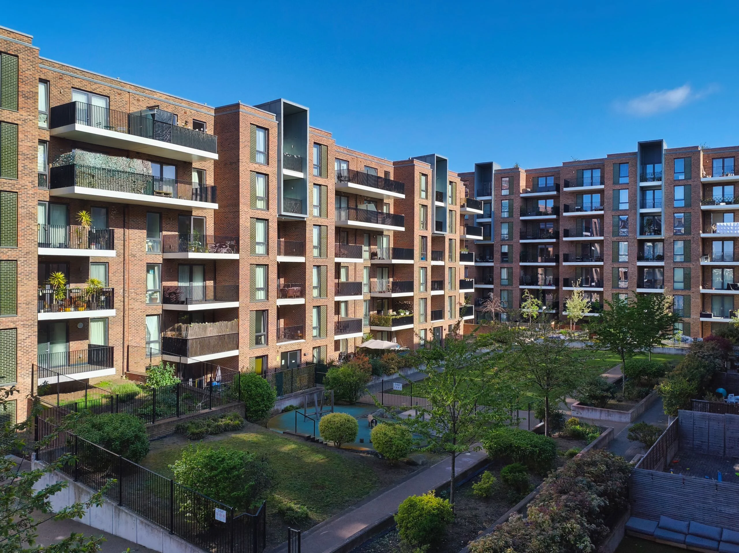Modern brick apartment complex with balconies and communal gardens