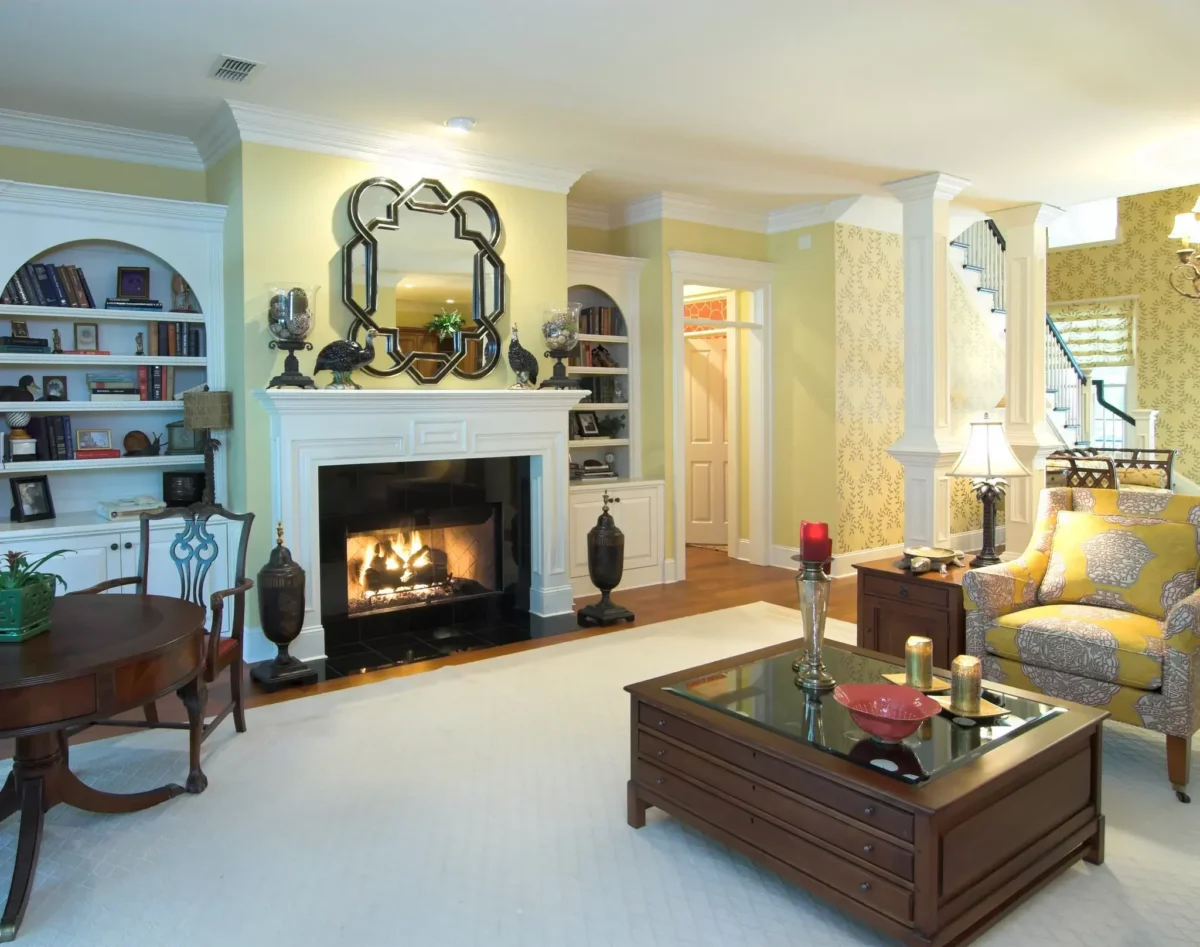 Classic living room with a lit fireplace, built-in white bookcases, and elegant furnishings before moving