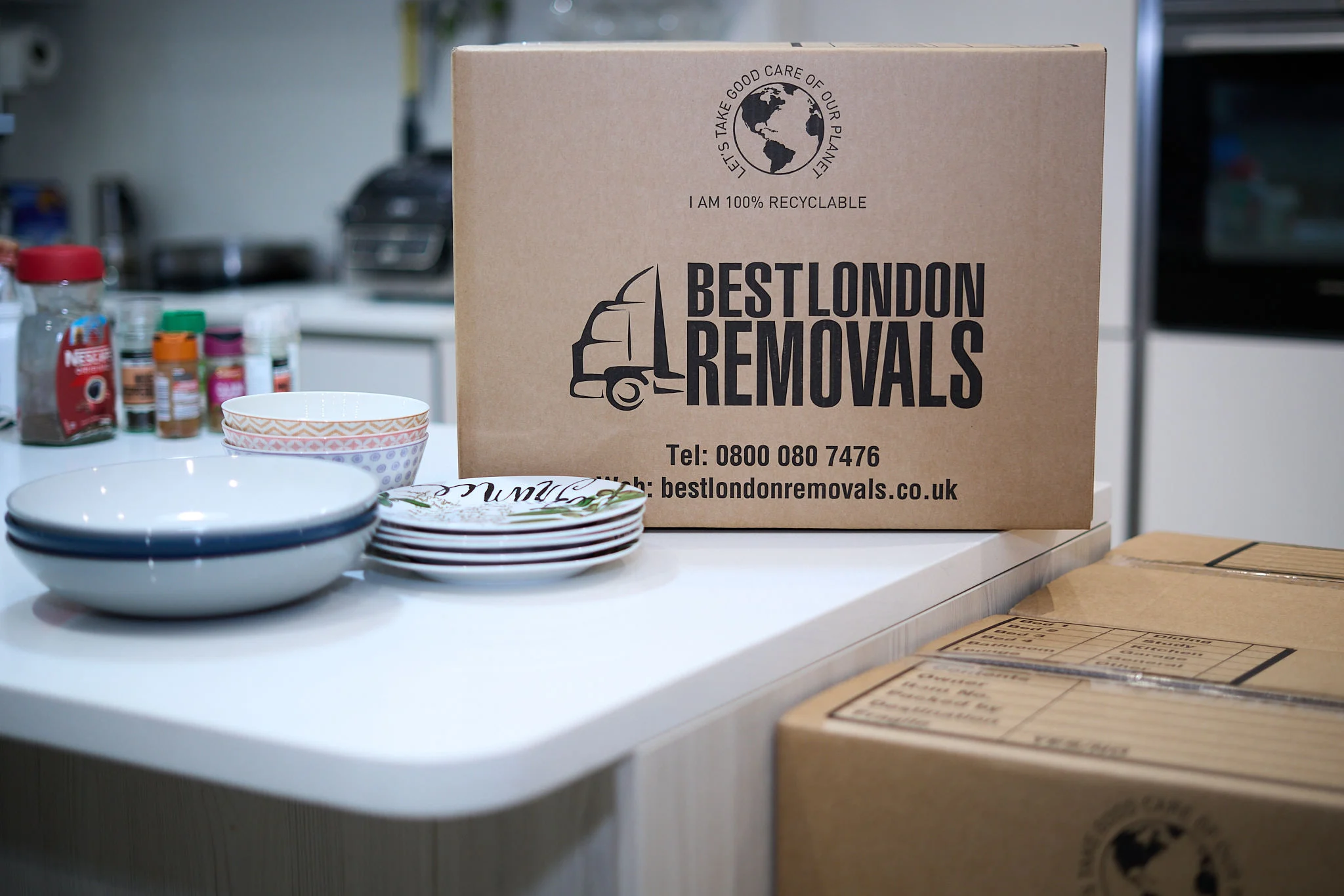 Branded Best London Removals box beside stacked bowls and plates, ready to be professionally packed