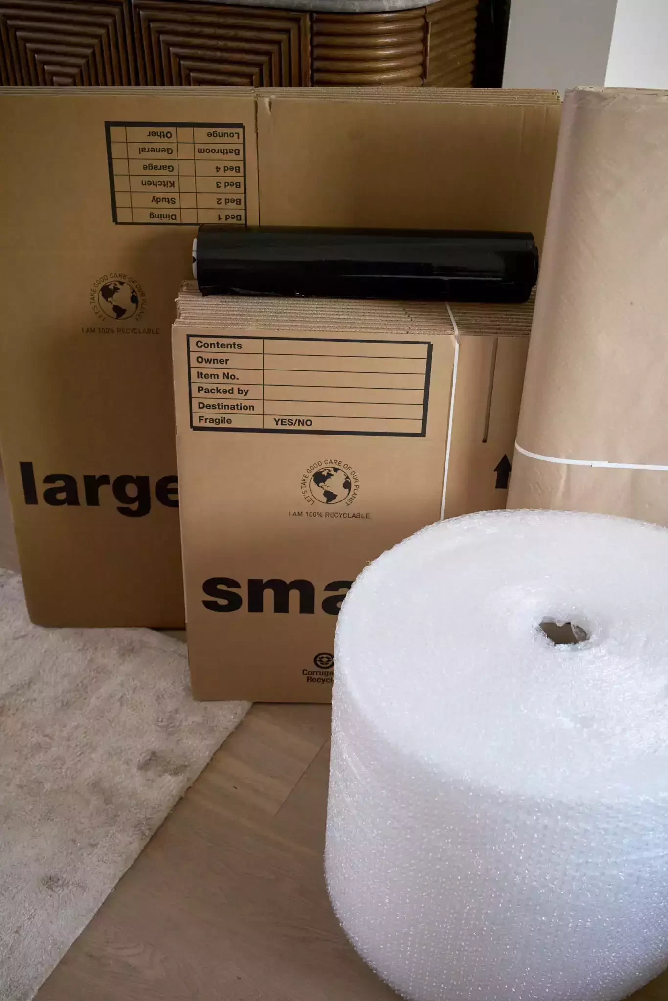 Cardboard moving boxes, bubble wrap, kraft paper and black shrink wrap ready for packing
