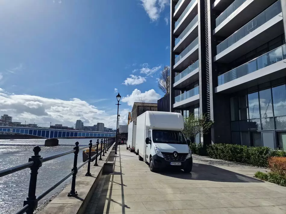 Removal van parked outside a luxury riverside apartment building in London during a professional move.