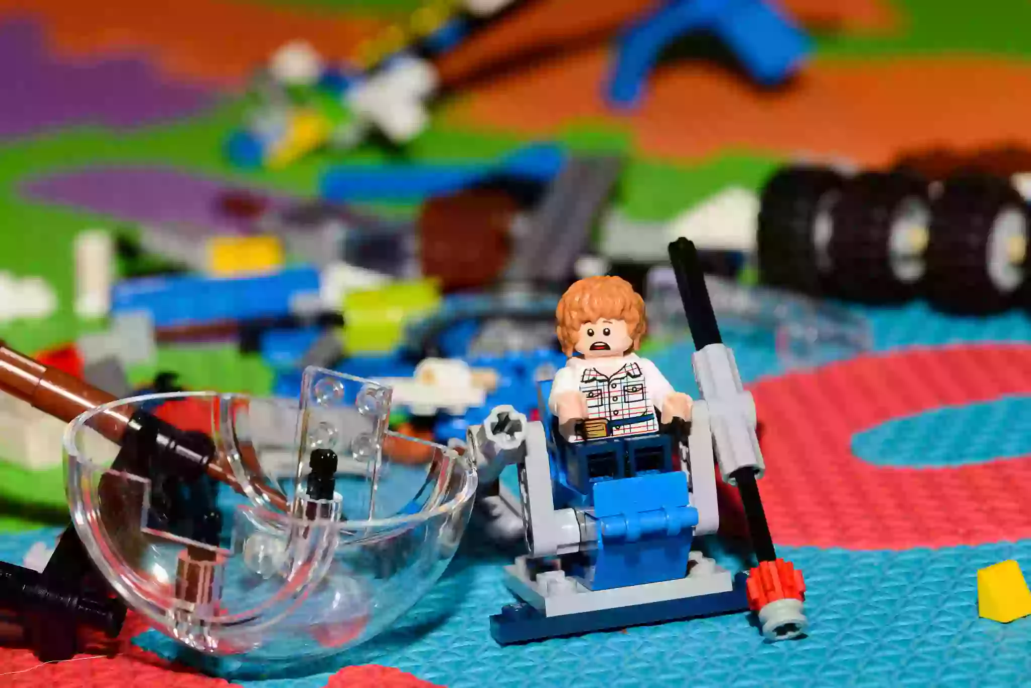 Scattered Lego pieces and a toy figure on a colourful playmat, symbolising moving with kids