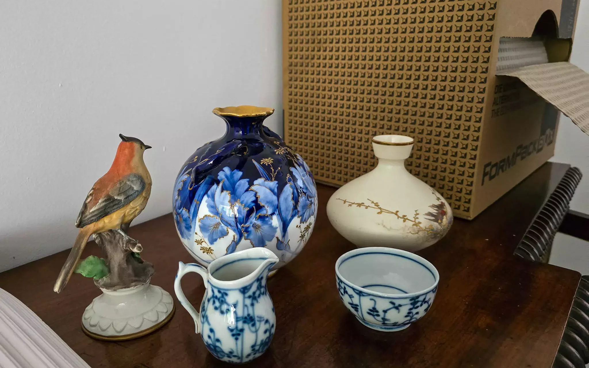 Delicate porcelain vases and figurines on a table next to a FormPack eco-wrap box.