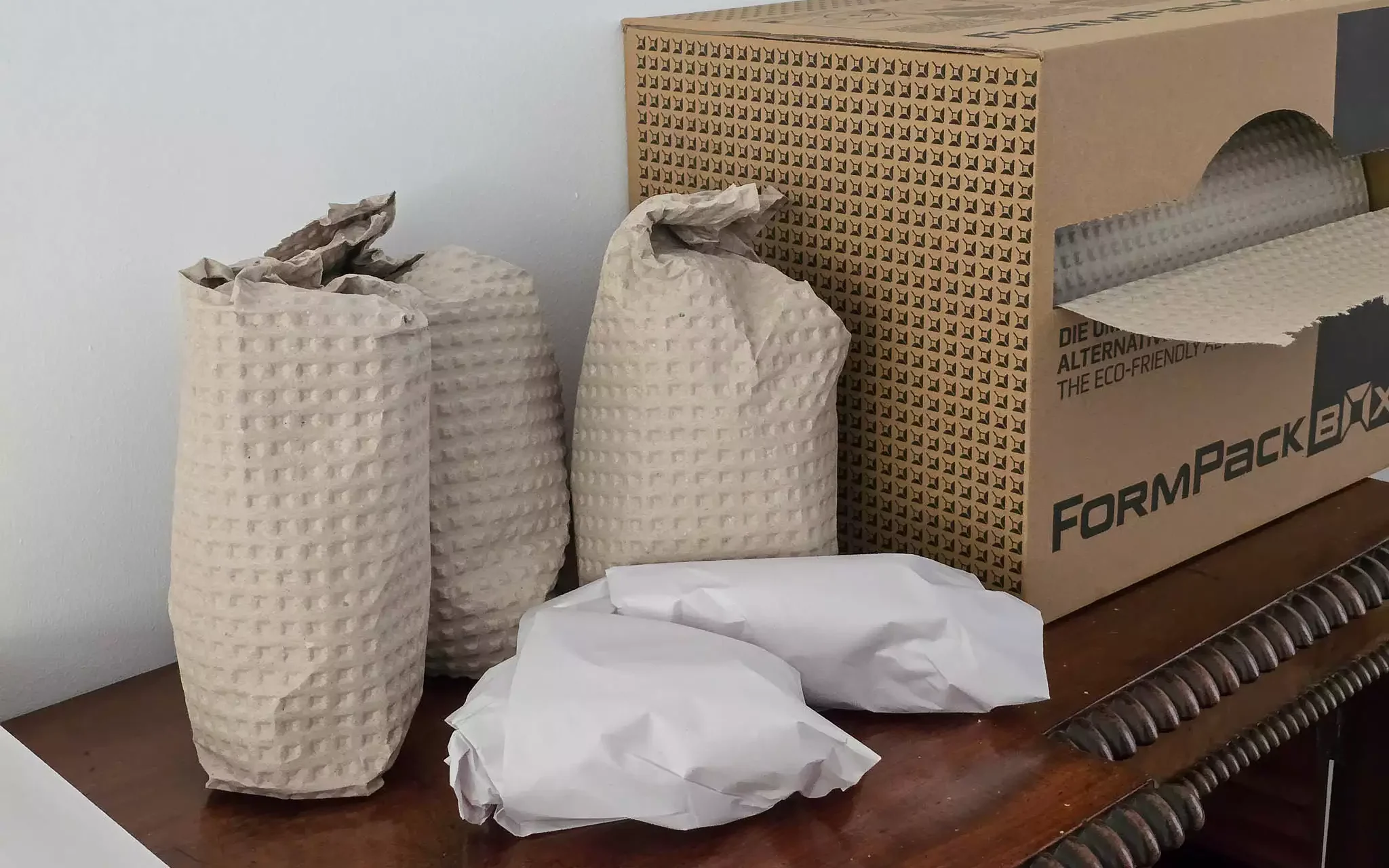 Packed ornaments – eco-safe and protected Ornaments wrapped in protective FormPack and paper, placed beside an open eco-wrap dispenser box.