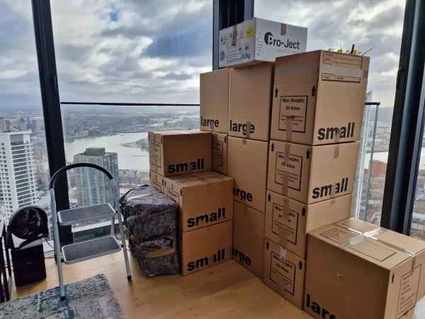 Moving boxes stacked inside a high-rise apartment with city views, prepared for a London relocation.