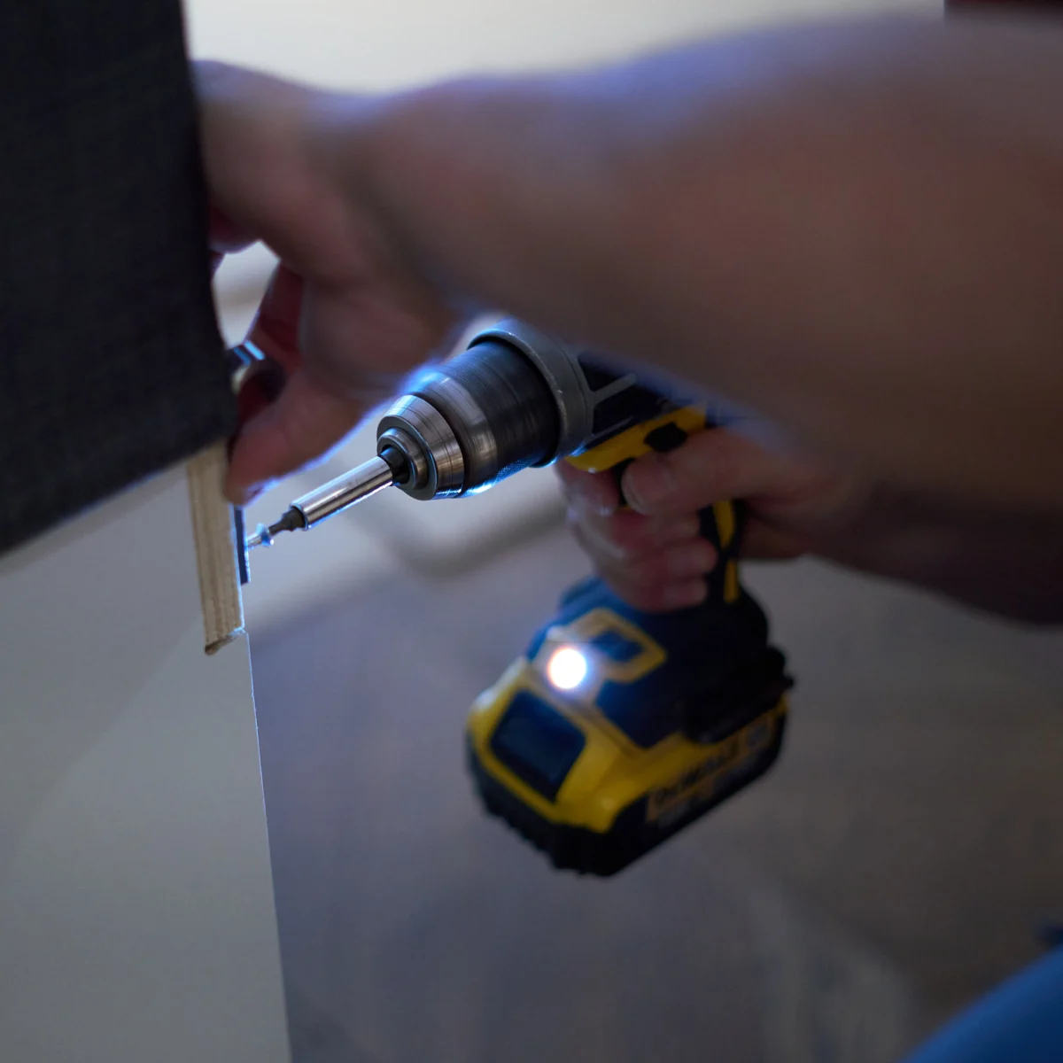 Close-up of a professional using a power drill to dismantle or assemble a piece of furniture 