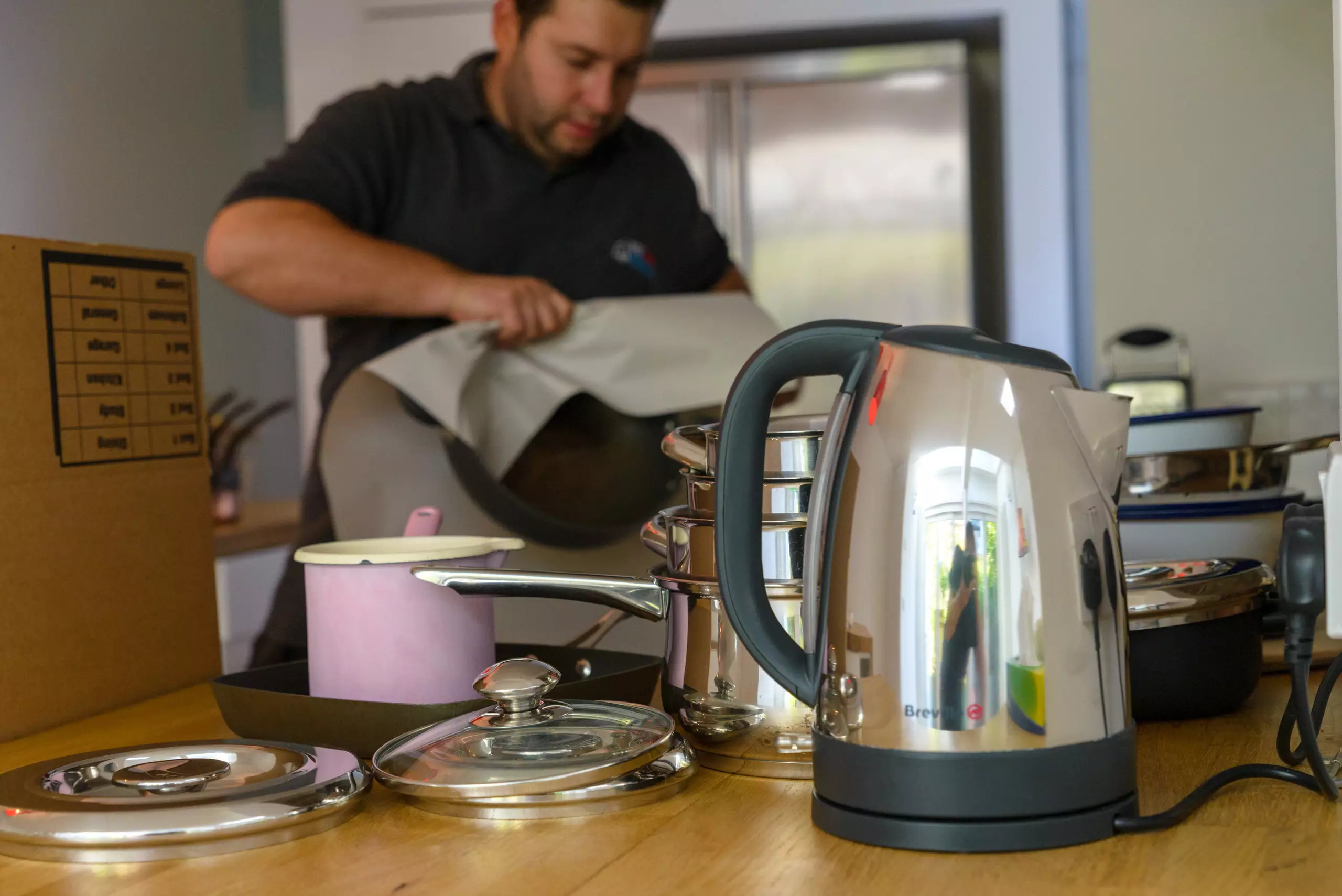 Mover packing kitchen items like kettles, pots, and cookware for a house move