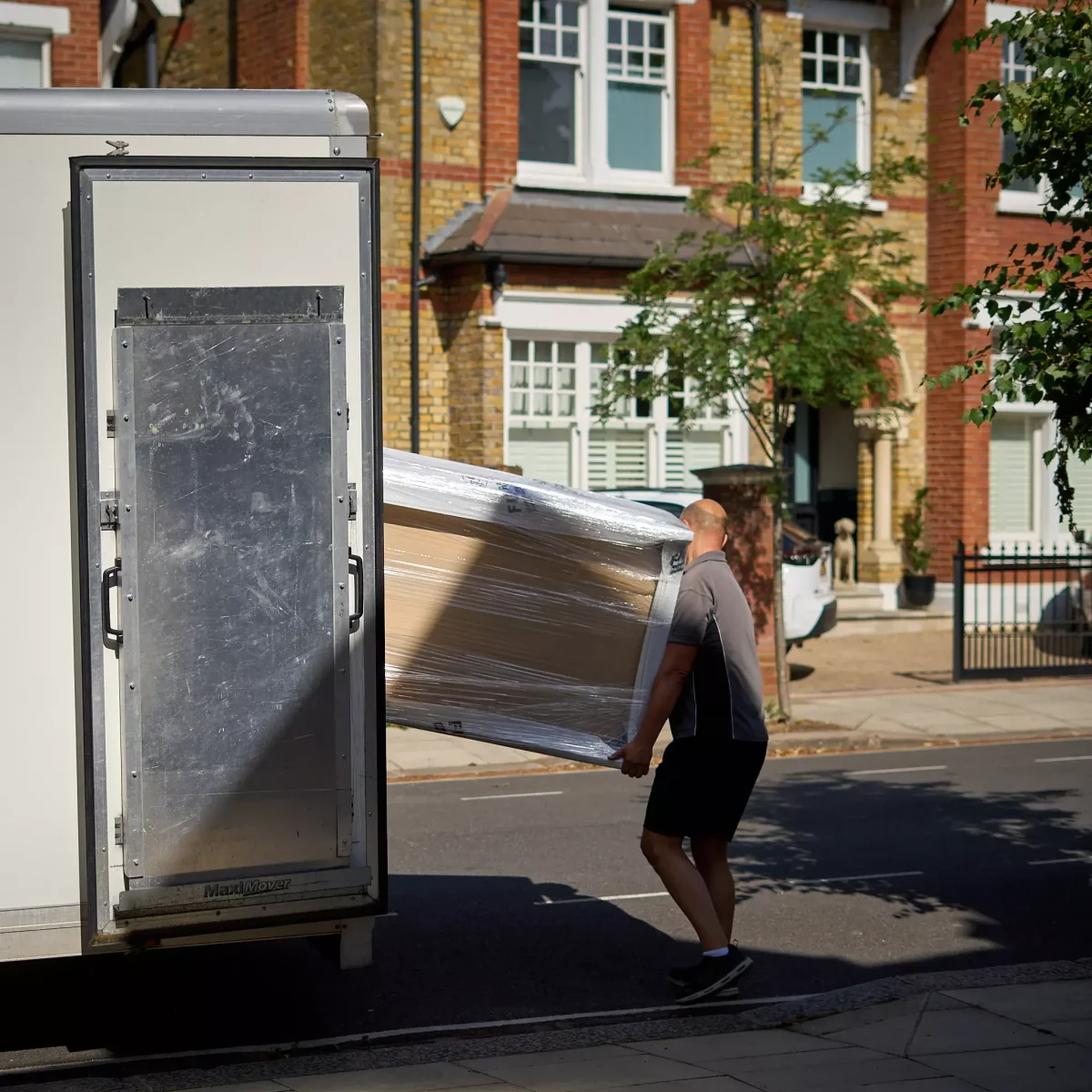 Movers loading wrapped furniture into van outside a home in Ealing during a house move.