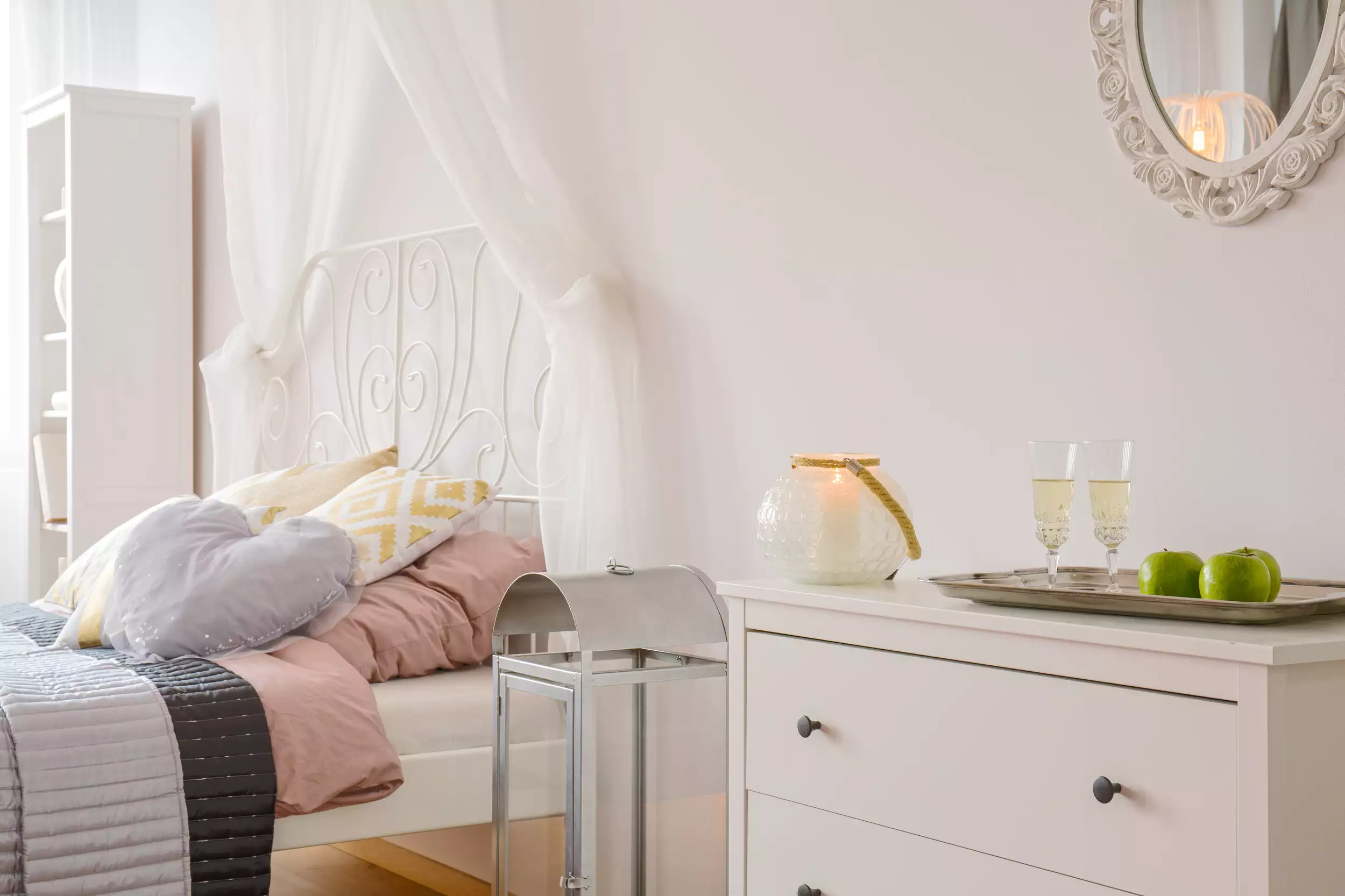 Tidy bedroom with white furniture, soft cushions, and styled décor ready for moving or packing.