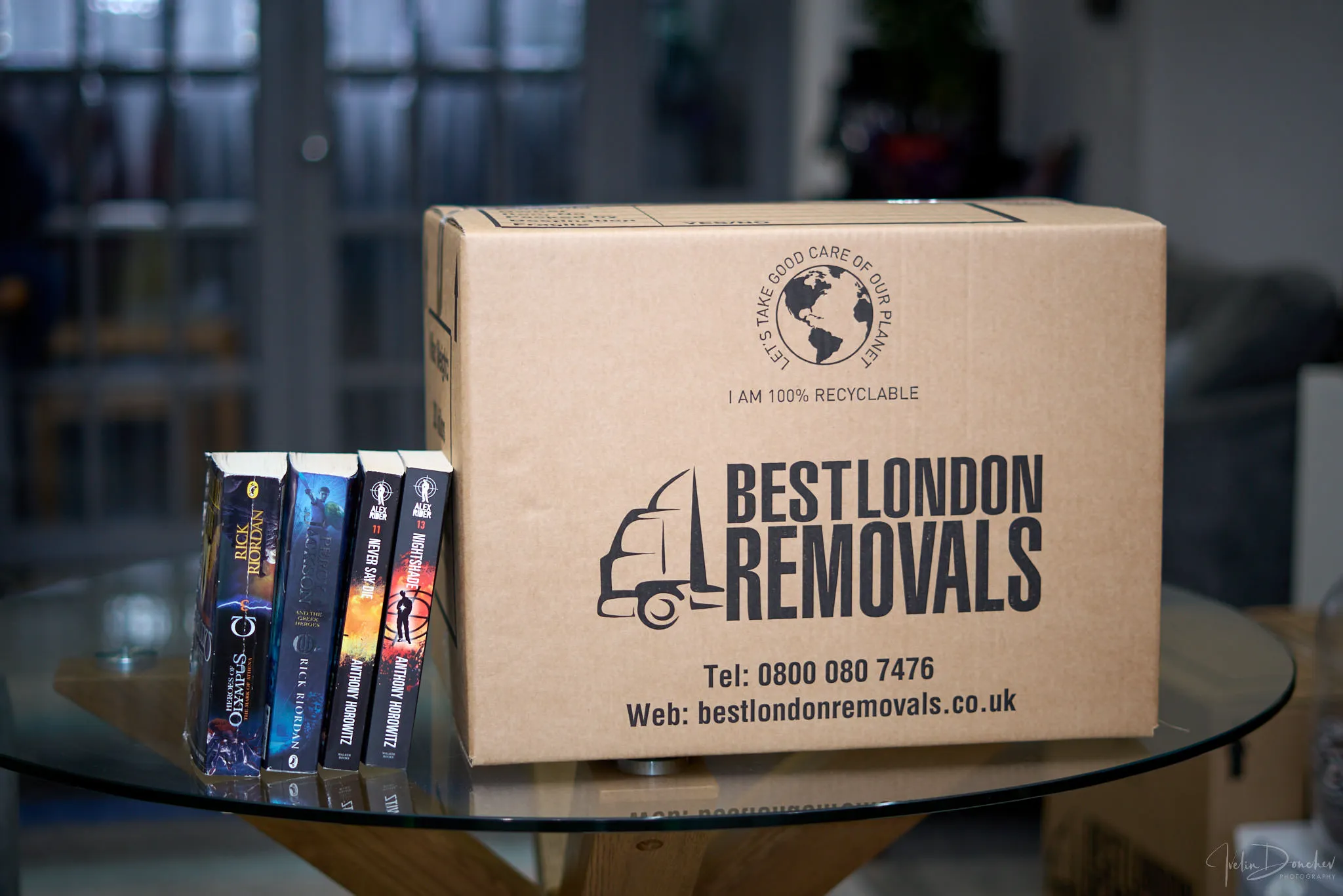 Best London Removals branded moving box on a glass table next to a stack of books