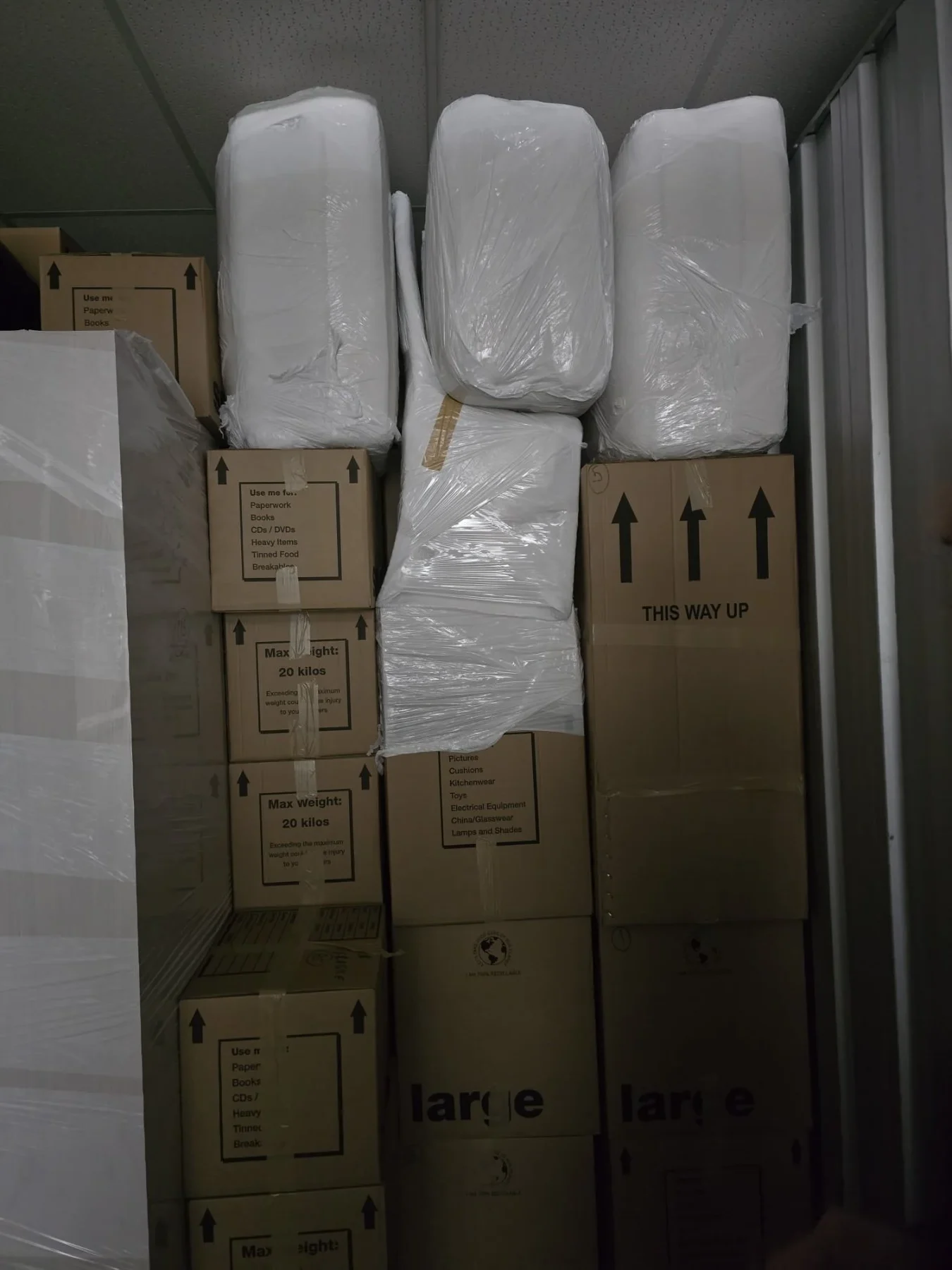 Stacked moving boxes and plastic-wrapped items in storage
