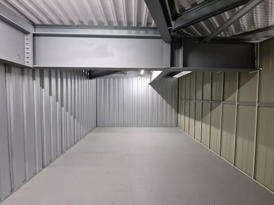 Interior of a storage unit showing a structural pillar and overhead beam obstructing usable floor and ceiling space