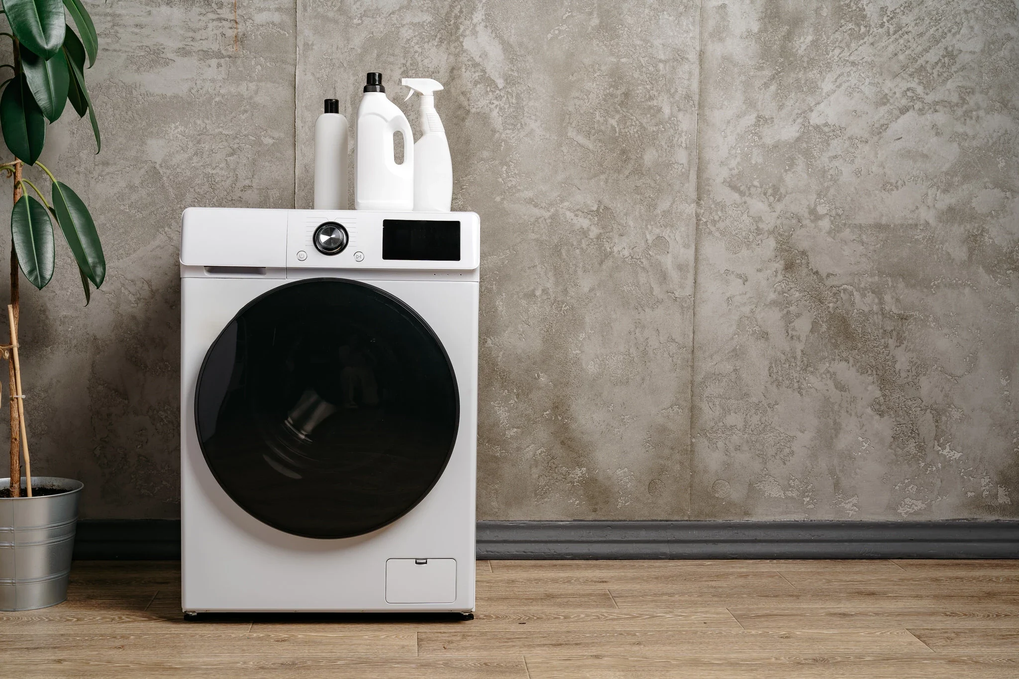 Freestanding washing machine with detergent bottles in a modern laundry room