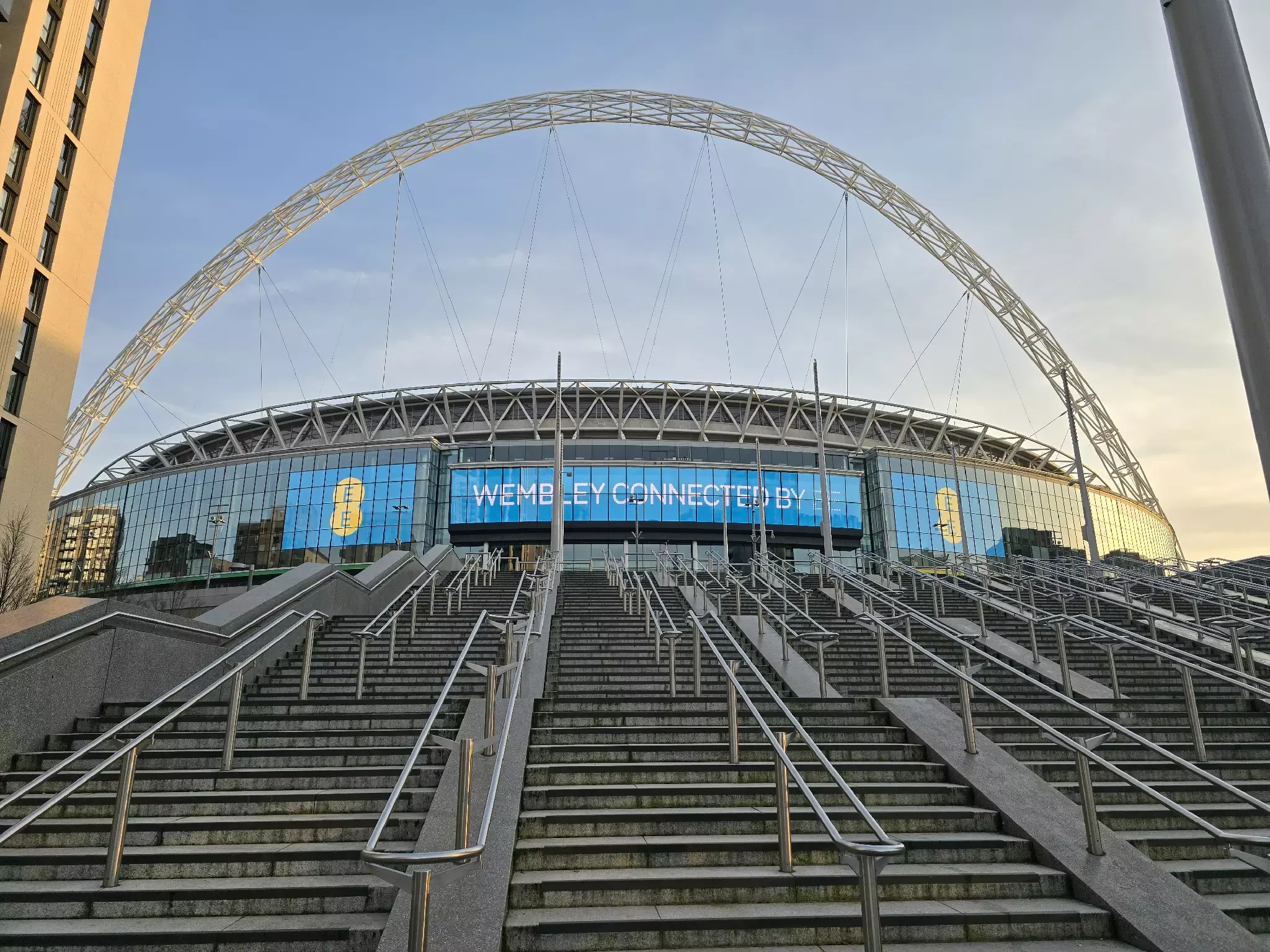Wembley Stadium arch above entrance steps at dusk